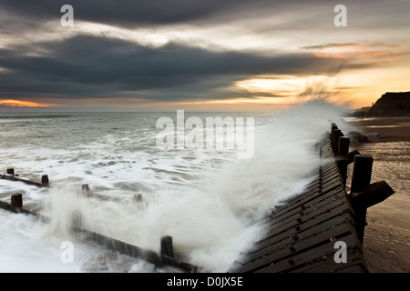 Les vagues se briser sur les défenses maritimes côtières à Happisburgh à Norfolk. Banque D'Images