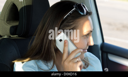 Femme avec sa tête incliné à parler sur son téléphone portable tout en étant assis dans la voiture Banque D'Images