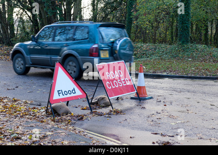 Hiver 2012 dans les inondations Lacock Wiltshire Angleterre. Voiture passant devant un panneau indiquant que la route est fermée Banque D'Images