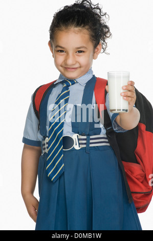 Portrait d'une lycéenne tenant un verre de lait et smiling Banque D'Images