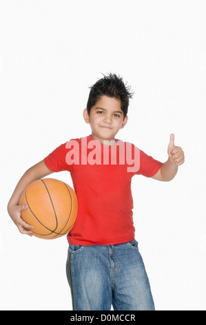 Boy holding a basket-ball et montrant un Thumbs up sign Banque D'Images