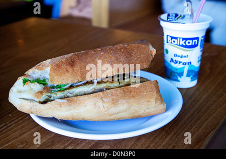 Balik ekmek (poisson) sandwich mangé sous le pont à Eminonu, Istanbul. Servi avec l'ayran, boisson traditionnelle. Banque D'Images