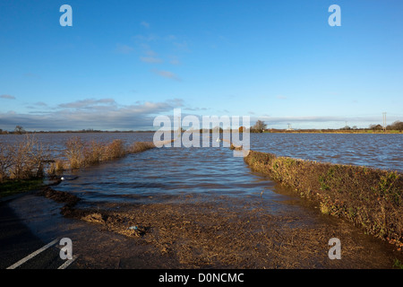 Un petit chemin rural submergée par les eaux des crues d'hiver sous un ciel bleu clair Banque D'Images