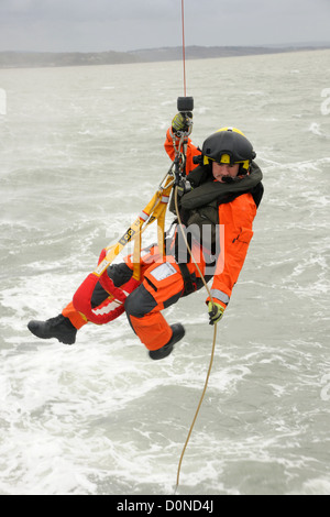 Un hélicoptère de garde-côtes winchman est abaissée à un bateau sur un jour de tempête Banque D'Images