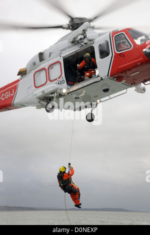 Hélicoptère de sauvetage de la Garde côtière s'abaisse un homme d'équipage Banque D'Images