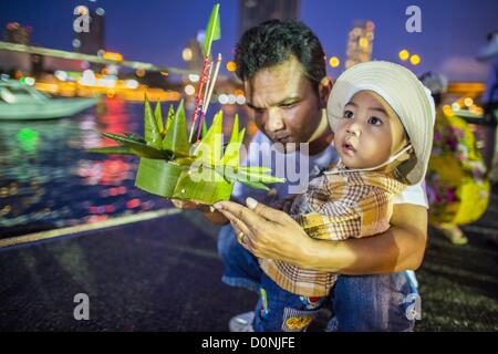 28 novembre 2012 - Bangkok, Thaïlande - un homme aide son fils à lancer leur krathong Loy Krathong lors du Wat Yannawa à Bangkok. Loy Krathong a lieu le soir de la pleine lune du 12e mois dans le calendrier lunaire traditionnel thaïlandais. Dans le calendrier occidental cette tombe habituellement en novembre. Loy signifie "float", tandis que se réfère à l'krathong habituellement contenant en forme de lotus qui flotte sur l'eau. Les Krathongs illumines traditionnelles sont faites de couches du tronc d'un bananier ou un spider lily plante. Credit : ZUMA Press, Inc. / Alamy Live News Banque D'Images