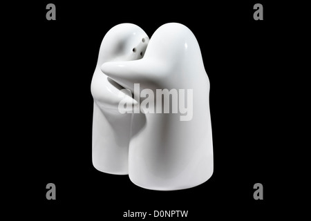 Étreindre en céramique blanche Sel et poivre pot isolé sur fond noir qui forment un symbole Ying Yang lorsque vues de dessus Banque D'Images