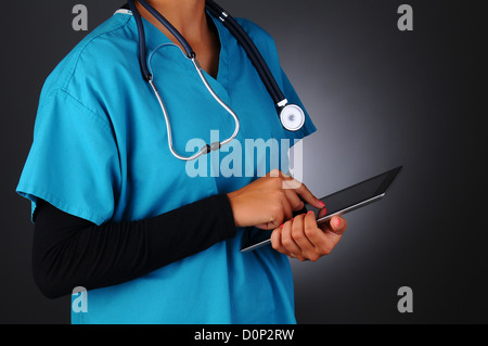 Libre d'un professionnel de la santé des femmes portant des gommages corporels en prenant des notes sur un ordinateur tablette. Banque D'Images