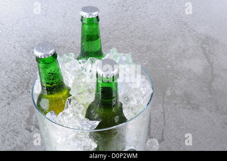 Trois bouteilles de bière verte dans un seau à glace en cristal. High angle avec copie espace sur le côté droit. Format horizontal. Banque D'Images