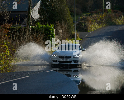 Voiture roulant dans de l'eau stagnante sur la route inondée, Cumbria, Angleterre, Royaume-Uni Banque D'Images