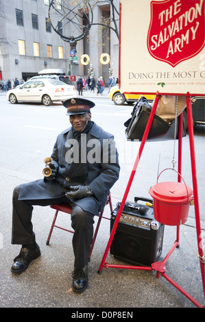 Sonnerie de cloche bénévoles afro-américaine recueille des dons pour l'Armée du Salut en face de Saks Fifth Avenue à Manhattan. Banque D'Images