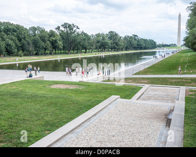 Lincoln Memorial Reflecting Pool Washington Monument with People / WASHINGTON D.C., États-Unis — les visiteurs parcourent le périmètre du Lincoln Memorial Reflecting Pool sur le National Mall, avec le Washington Monument visible au loin. La piscine a été reconstruite entre 2010 et 2012 après des fuites chroniques et des problèmes d'algues - la rénovation a remplacé l'infrastructure d'origine des années 1920 par un système de recirculation de filtration et a abaissé la profondeur de l'eau à environ 18 pouces (46 cm). Banque D'Images