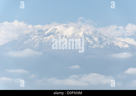 MONT KILIMANDJARO, Tanzanie — le sommet (sommet de Kibo) du Mont Kilimandjaro vu de la distance ci-dessous, avec sa neige et partiellement couvert de nuages. Banque D'Images