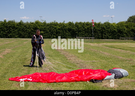 Parachutiste senior a atterri le sauvegarder sur une pelouse après une skydive. Il obtient son parachute ensemble dans la zone d'atterrissage. Banque D'Images