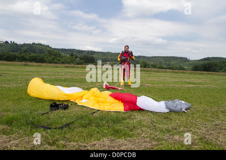 Cette fille débarque avec son parachutiste parachute et est maintenant très heureux d'être enregistrer sur le sol. Banque D'Images