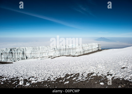 MONT KILIMANDJARO, Tanzanie — les glaciers de glace sont en permanence sur le sommet du Mont Kilimandjaro, bien qu’ils diminuent rapidement avec le changement climatique. À droite du cadre au loin se trouve le sommet du Mont Meru piquant à travers les nuages. Banque D'Images