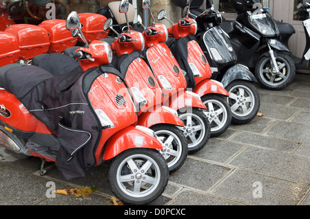 Paris, France : Rouge Piaggio Vespa scooters en location - parqué dans une rangée à l'extérieur d'un magasin de location. Banque D'Images