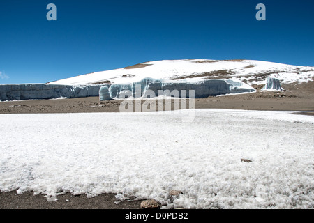 MONT KILIMANDJARO, Tanzanie — de épais champs de glace recouvrent un glacier sur le plateau près de Crater Camp à 18 810 pieds d'altitude, situé juste en dessous du sommet Kibo sur le Mont Kilimandjaro. Le camp sert de point d'étape en haute altitude pour les grimpeurs tentant d'atteindre le pic Uhuru, le point culminant de la montagne à 19 341 pieds. Le Kilimandjaro, la plus haute montagne d'Afrique, présente trois cônes volcaniques, dont Kibo, qui contient le cratère sommital. Les champs de glace glaciaires représentent une partie de la calotte glaciaire en diminution de la montagne, qui a considérablement reculé au cours des dernières décennies. Crater Camp est parmi les th Banque D'Images