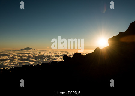 Le mont Kilimandjaro, Tanzanie - Le sommet du Mont Meru pokes à travers les nuages tandis que le soleil se couche à l'horizon comme vu à partir de la flèche située sur le glacier du Kilimandjaro Lemosho Route. Banque D'Images