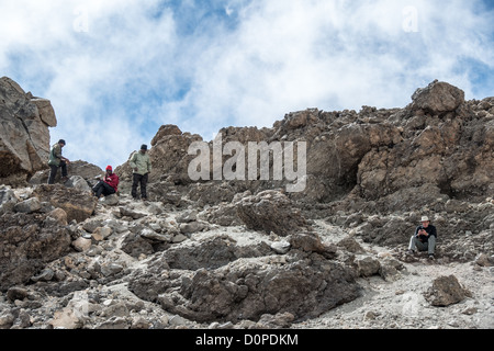 MONT KILIMANDJARO, Tanzanie — Un grimpeur et des porteurs trouvent un endroit avec une réception de téléphone portable rare parmi les rochers près du sommet du Mont Kilimandjaro. Banque D'Images