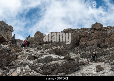 MONT KILIMANDJARO, Tanzanie — Un grimpeur et des porteurs trouvent un endroit avec une réception de téléphone portable rare parmi les rochers près du sommet du Mont Kilimandjaro. Banque D'Images