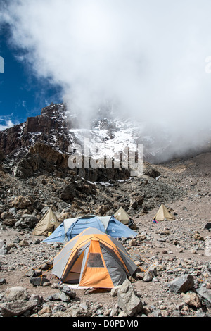 MONT KILIMANDJARO, Tanzanie — des tentes sont positionnées au camp du glacier Arrow le long de la route Lemosho du Mont Kilimandjaro, avec la brèche occidentale visible en arrière-plan. Arrow Glacier Camp sert de camping de haute altitude pour les grimpeurs qui montent le plus haut sommet d'Afrique via la route Lemosho, l'une des nombreuses routes d'escalade établies sur la montagne. La brèche occidentale représente une route d'escalade technique difficile qui permet d'accéder au bord du cratère du Kilimandjaro. Le mont Kilimandjaro, qui culmine à 19 341 pieds, est situé dans le nord de la Tanzanie, près de la frontière avec le Kenya. La route Lemosho est widel Banque D'Images