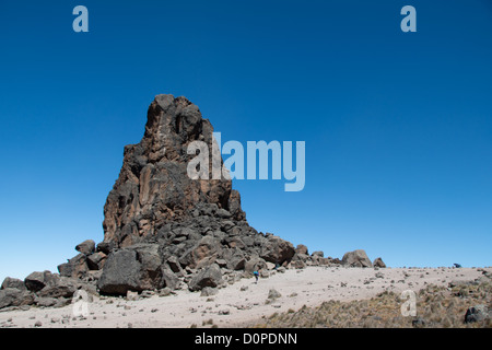 MONT KILIMANDJARO, Tanzanie — Un porteur passe devant la base de la tour de lave face à un ciel bleu clair sur la route Lemosho du Mont Kilimandjaro. Banque D'Images