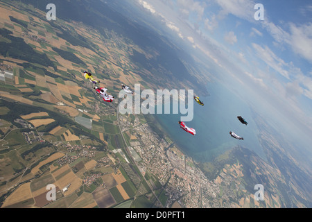 Les parachutistes Wingsuit flying sont ensemble dans une flèche formation au-dessus de paysage magnifique paysage et avoir du plaisir. Banque D'Images