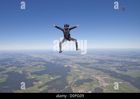 Fun diver est la chute libre à travers le ciel bleu dans une position s'asseoir et attendre que ses collègues de jouer avec eux. Banque D'Images