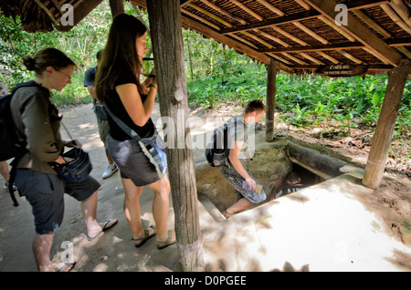 Entrée touristique Ho Chi Minh-ville Vietnam // HO CHI Minh-VILLE, Vietnam — les touristes descendent dans une section préservée du complexe de tunnels de Cu Chi, un vaste réseau souterrain qui a servi de base cruciale pour les opérations pendant la guerre du Vietnam. Le système de tunnels, situé au nord-ouest de Ho Chi Minh-ville, s'étendait sur des centaines de kilomètres et abritait des communautés entières sous terre. Cette section préservée a été partiellement élargie pour accueillir les visiteurs tout en conservant son importance historique. Les tunnels servent maintenant de site historique populaire, permettant aux visiteurs d'experi Banque D'Images