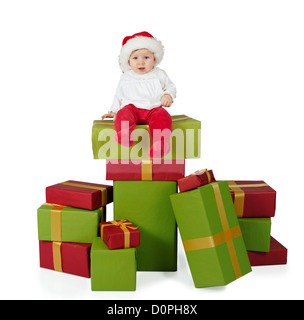 Bébé assis sur une pile de cadeaux de noël, isolé sur fond blanc Banque D'Images