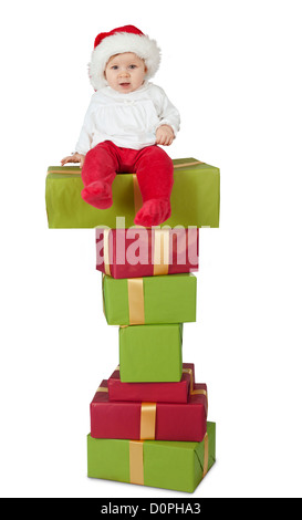 Bébé assis sur une pile de cadeaux de noël, isolated on white Banque D'Images