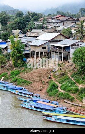 Nong Khiaw Village Waterfront Laos // NONG KHIAW, Laos — des maisons bordent le front de mer dans le village de Nong Khiaw, dans le nord du Laos. La colonie se trouve le long de la rivière Nam ou dans la province de Luang Prabang, positionnée entre des montagnes karstiques calcaires spectaculaires. Nong Khiaw sert de passerelle vers le nord rural du Laos et est couramment utilisé comme base pour explorer le terrain montagneux environnant. Le village s'est développé comme une halte le long de la route de la rivière Nam ou reliant Luang Prabang à la frontière chinoise. La région fait partie de la région plus large du nord du Laos connue pour son commun rural lao traditionnel Banque D'Images