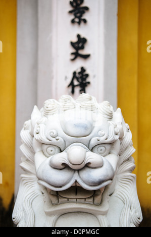 HANOI, Vietnam — des lions de marbre blanc richement sculptés gardent l'entrée d'une porte à la pagode One Pillar à côté du musée Ho Chi Minh dans le quartier Da Binh de Hanoi, Vietnam. Caractères vietnamiens en arrière-plan. Banque D'Images