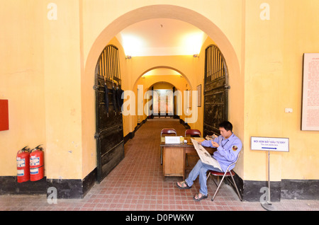 HANOI, Vietnam — Un gardien est assis à l'entrée principale du musée de la prison de Hoa Lo pour recueillir les billets des visiteurs. La prison de Hoa Lo, également connue sarcastiquement sous le nom de Hanoi Hilton pendant la guerre du Vietnam, était à l'origine une prison coloniale française pour prisonniers politiques, puis une prison nord-vietnamienne pour prisonniers de guerre. Il est particulièrement célèbre pour être la prison utilisée pour les pilotes américains abattus pendant la guerre du Vietnam. Banque D'Images