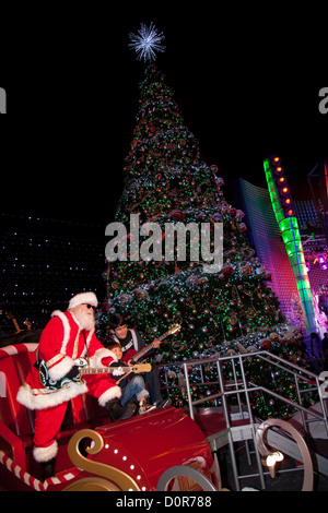 Un garçon posant avec Rockin' Santa à Universal CityWalk à Los Angeles, CA Banque D'Images