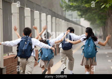 Vue arrière de la ville animée d'écoliers en uniforme sur le chemin de l'école Banque D'Images