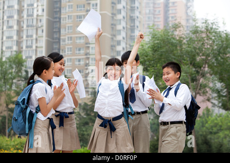 Cheerful écoliers en uniforme pour célébrer leurs résultats de tests Banque D'Images