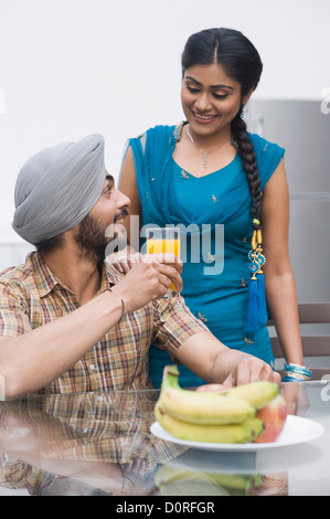 L'homme de boire de jus d'orange avec sa femme debout à côté de lui Banque D'Images