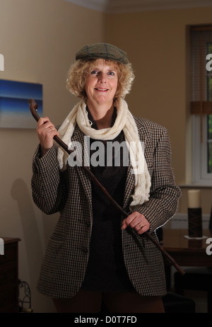 Femme d'âge moyen portant un mens Harris Tweed veste et casquette avec de vieux bâton de marche Photo prise par Simon Dack Banque D'Images