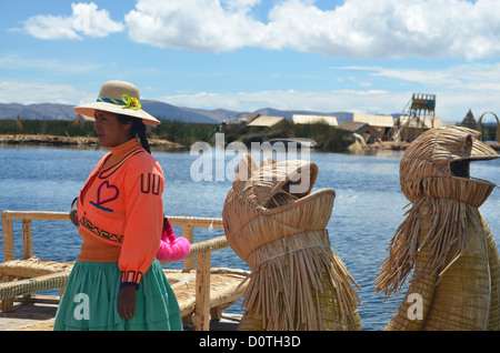 Dame indigènes se place en avant de son bateau sur la lecture Tortora îles Uros du Lac Titicaca, près de Puno, Pérou. Banque D'Images