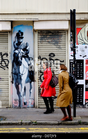 Deux femelles en passant devant certains street art de Londres E1 UK Banque D'Images