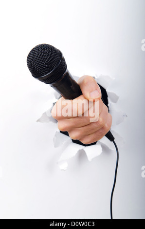 Microphone main tenant par le trou dans le papier Banque D'Images