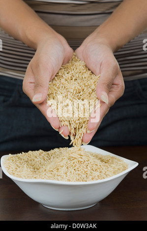 Mid section view of a woman pouring dans un bol de riz brun Banque D'Images