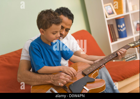 L'homme d'aider son fils en jouant de la guitare Banque D'Images