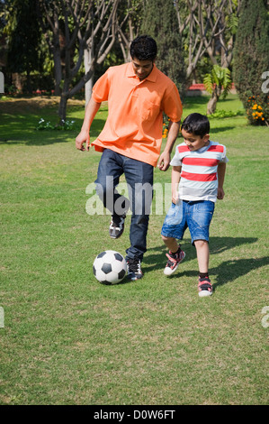 L'homme et son fils jouant avec un ballon de soccer, Gurgaon, Haryana, Inde Banque D'Images