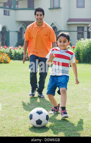 L'homme et son fils jouant avec un ballon de soccer, Gurgaon, Haryana, Inde Banque D'Images