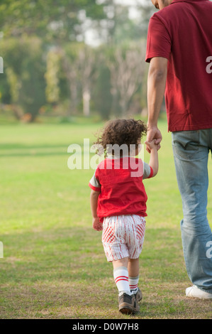 Vue arrière d'un homme qui marche avec son fils Banque D'Images