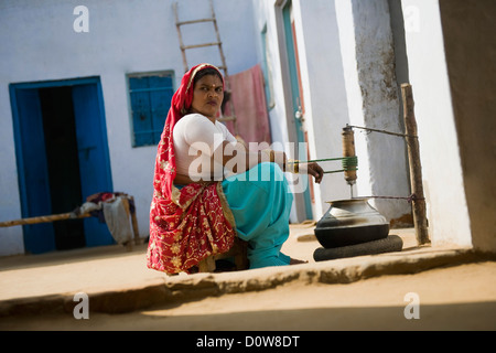 Le barattage du beurre, femme Farrukh Nagar, Gurgaon, Haryana, Inde Banque D'Images