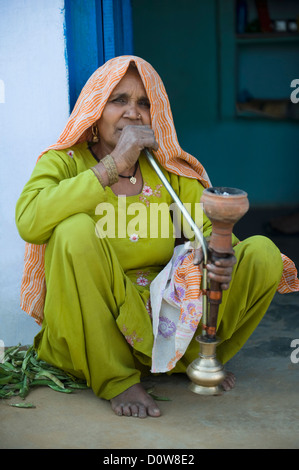 Femme fumant un narguilé pipe, Farrukh Nagar, Gurgaon, Haryana, Inde Banque D'Images